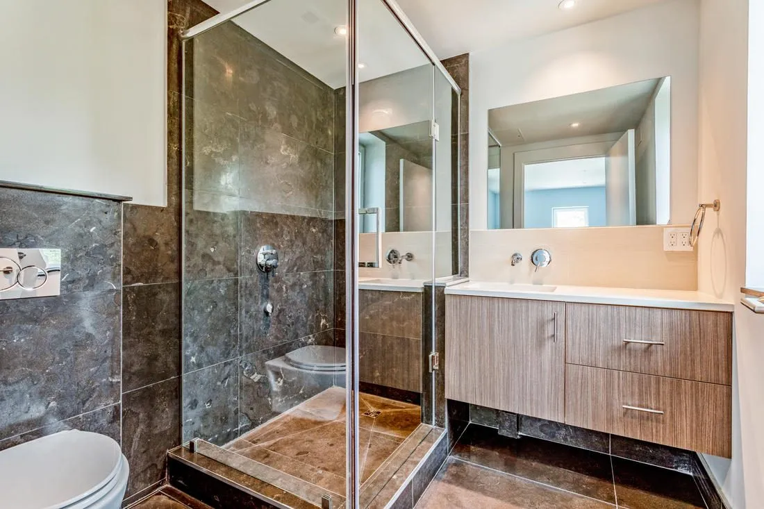 Wall-hung toilet and vanity with drawers next to a glass shower