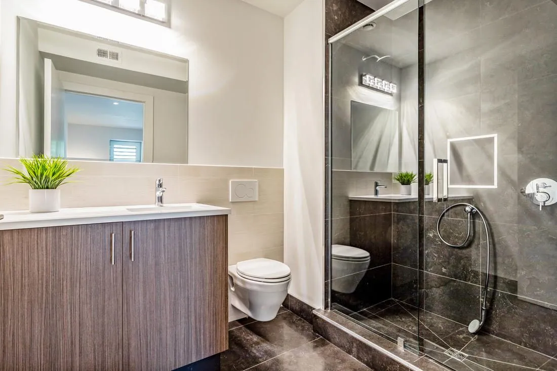 Frameless glass shower doors beside a wall-hung vanity