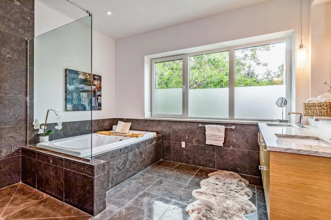 Soaking tub under a wide window with a stone surround