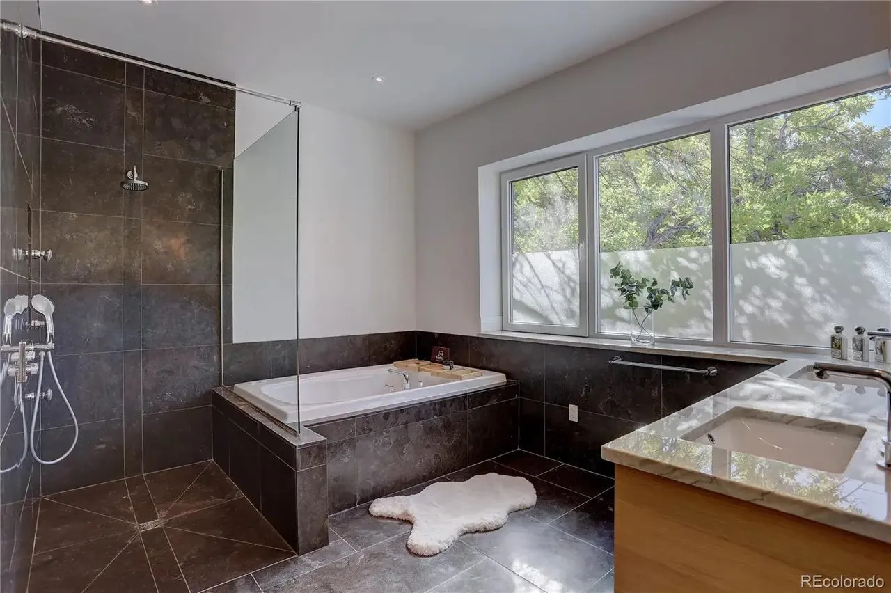 Primary bathroom with a stone-clad tub, walk-in shower, and floating wood vanity