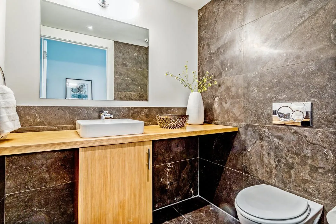 Wall-hung toilet and vessel sink on a wood counter