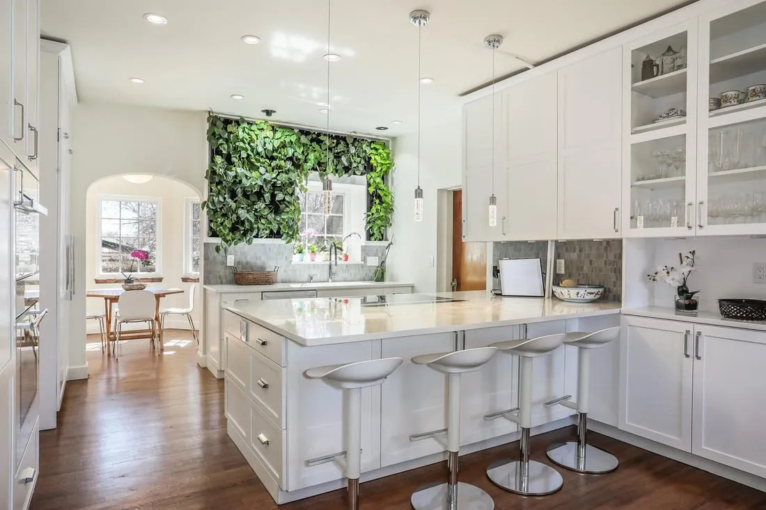 White kitchen island with seating and a living wall above the sink