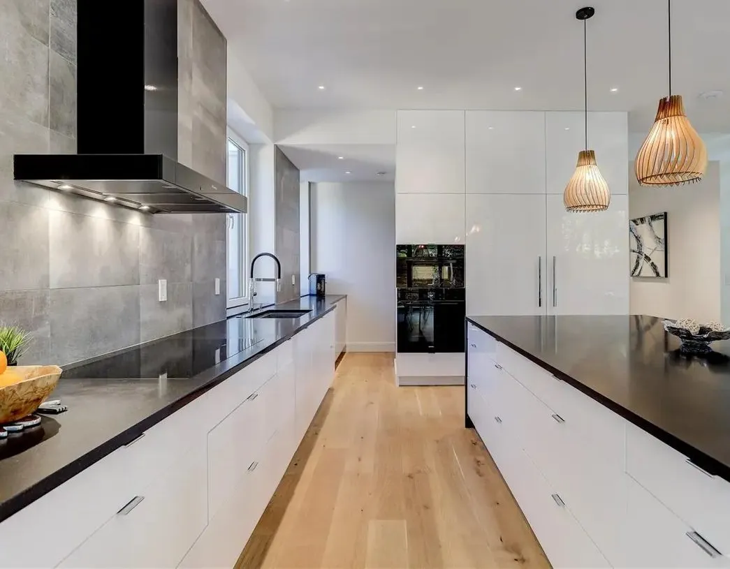 Black countertops and white flat-panel cabinets along a long galley