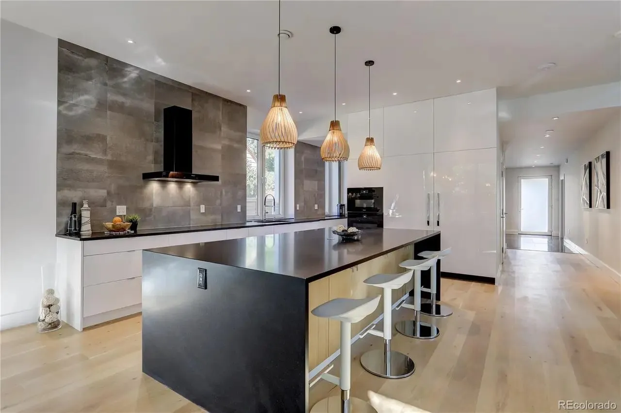 Contemporary kitchen with a black island and a tile hood wall