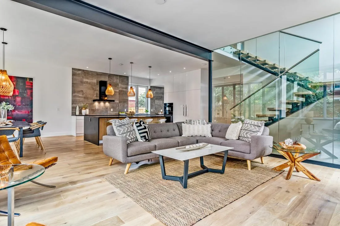 Open living room beside a glass-walled stair in a new custom home