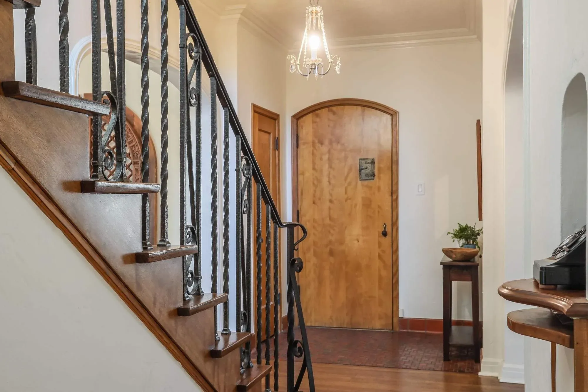 Entry hall with a wood staircase and arched door